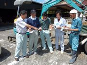 建築現場で職人さんに組合の説明をする植田支部長（左）