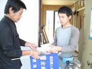 建設現場へ訪問し、組合未加入者の職人さんへ組合パンフレットを手渡す役員（左）