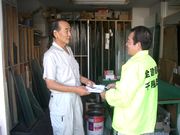 役員から熱心な組合説明を受け、組合パンフレットを受取るガラス店のご主人（左）