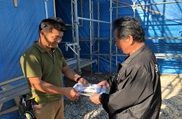新築現場を手掛ける職人へ組合パンフレットを渡す