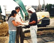 職人さんに組合パンフレットを渡し、熱心に組合メリットを説明する役員(中・左)