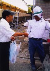 職人さんへタイル等を渡す田口支部長（左）