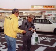 買い物を終えた職人さんに声掛けする役員(左)