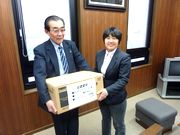 大工道具を手渡す書記長(左)